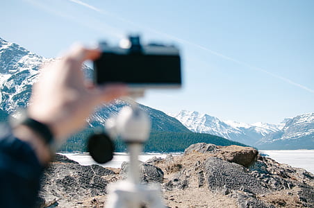 person holding camera facing mountains thumbnail