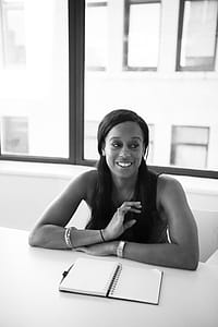 Grayscale Photography of Woman in Sleeveless Top Sits Near Table thumbnail