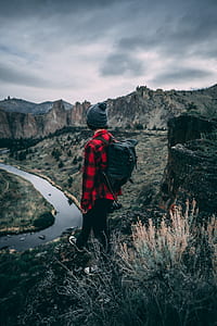 man in red and black plaid dress shirt on top of mountain during daytime thumbnail