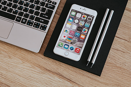 Silver Acer laptop, a white Apple iPhone and a notepad on a wooden desk thumbnail
