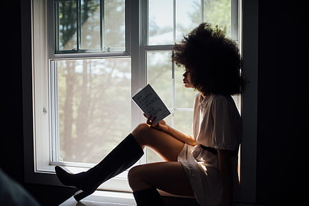 woman sitting on window reading book thumbnail