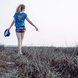 woman blue cage back crew-neck cap sleeve black short shorts while standing on a field holding fedora hat thumbnail