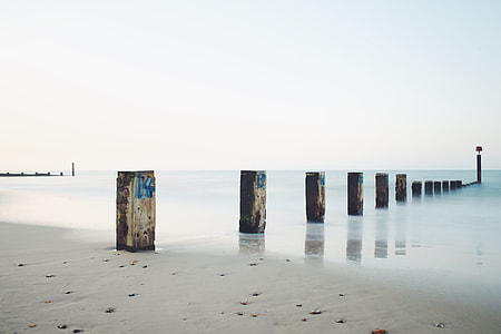 linear wooden pillars in sea under clear sky thumbnail