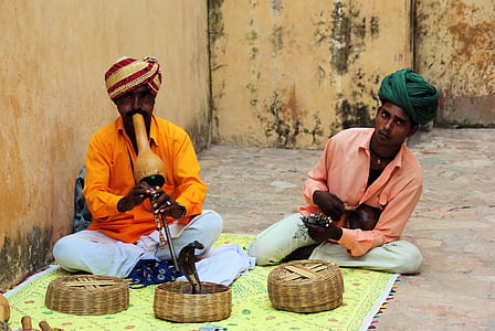 two men sitting on ground near brown baskets thumbnail