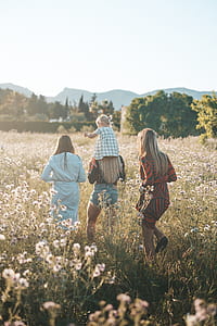 three women and girl walking on white petaled flower garden during daytime thumbnail