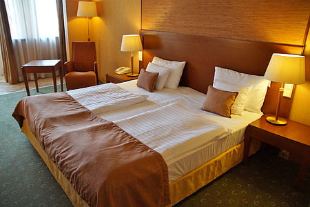bed between nightstand and table lamp thumbnail
