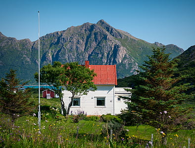white house on green grass in front of mountain thumbnail