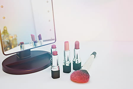 Four Assorted-color Lipsticks Beside Makeup Brush thumbnail