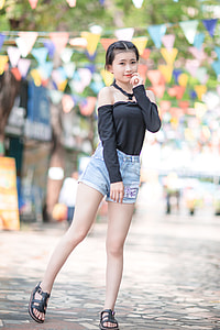 girl in black cold-shoulder blouse and blue stone-washed denim cuffed short shorts outfit having pictorial during daytime thumbnail
