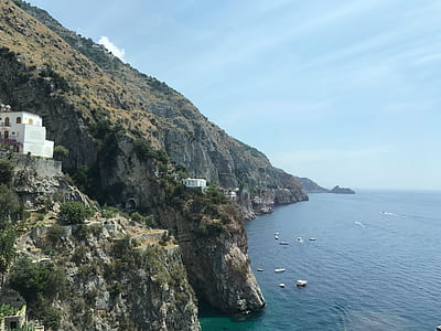 houses on cliff over body of water during daytime thumbnail