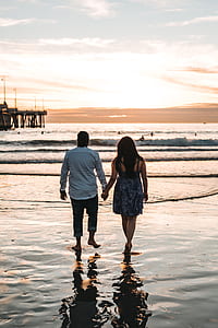 man and woman walking on sea shore thumbnail