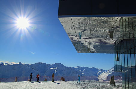 people standing near glass building front of alps thumbnail