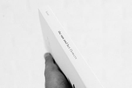 Grayscale Photo of Person Holding Book thumbnail
