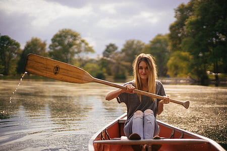 selective focus photography of woman paddling boat on body of water thumbnail