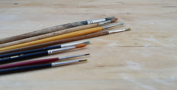 assorted-color paint brushes on brown table thumbnail