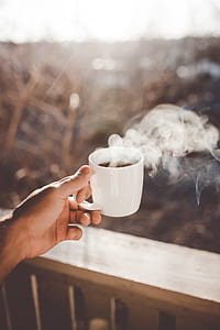 person's left hand holding cup of cofffee thumbnail
