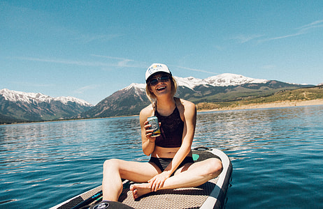 woman happily sitting on paddle board on sea with snow capped mountains background thumbnail