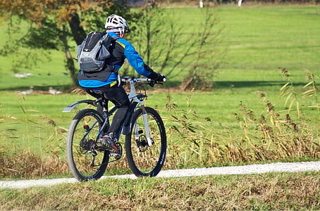 cyclist on pathway near between green grasses during daytime thumbnail