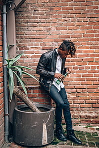 man leaning on brown bricked wall thumbnail