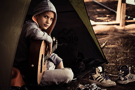 woman wearing gray hoodie while playing brown guitar photograph thumbnail