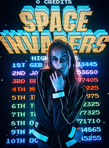 woman wearing black and yellow jacket behind Space Invaders game application thumbnail