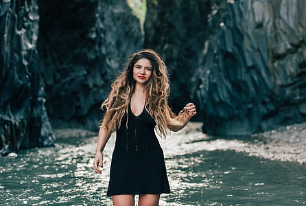 woman wearing black sleeveless dress beside body of water thumbnail