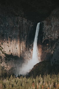 waterfall near pine trees at daytime thumbnail
