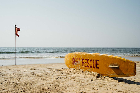 brown surf rescue surfboard near flag pole thumbnail