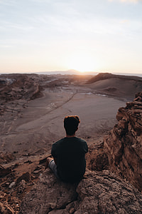 person sitting on rock cliff during daytime thumbnail