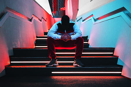 man wearing long-sleeved shirt and pants sitting on concrete stairs thumbnail