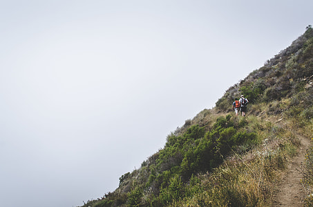 two men hiking on mountain towards summit at during daytime thumbnail