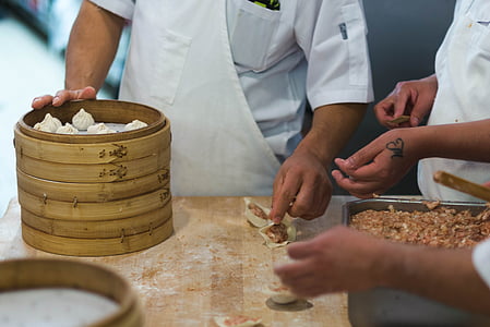 man holding shumai on brown wooden table thumbnail