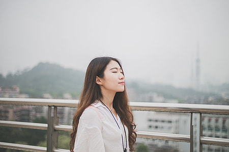 woman in white collared top taking photo beside silver handrails thumbnail
