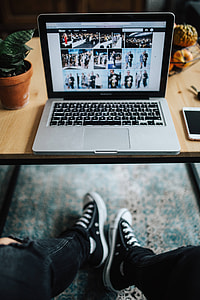 Woman in ripped jeans and black sneakers with a silver laptop on a wooden table thumbnail