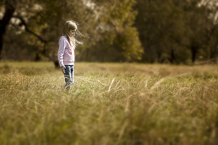girl in pink hoodie standing in grass field thumbnail