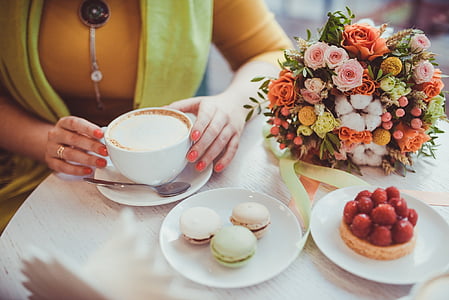 white ceramic cup on white saucer beside flower bouquet thumbnail