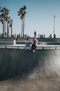 man and woman sitting on skate park surrounded by people thumbnail