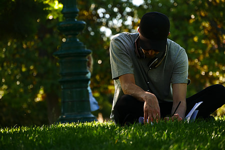 selective focus photography of woman writing on grass field thumbnail