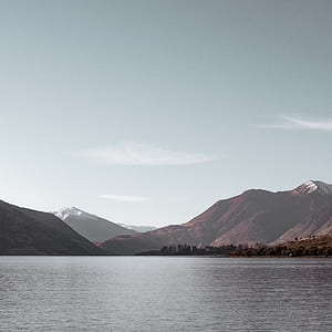 photo of lake near mountains under cloudy sky thumbnail