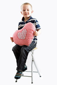 boy sitting on stool holding red heart pillow thumbnail