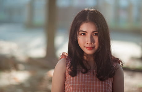 Selective Focus Photography of Woman With Pink and White Sleeveless Top Standing Behind Tree Trunk thumbnail