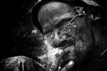 grayscale photography of man smoking cigarette thumbnail
