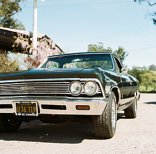 classic black coupe parked near trees thumbnail