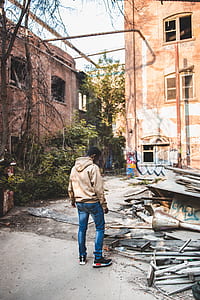 man standing on road leaning on ground near building thumbnail