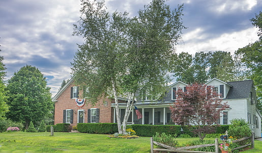 brown and white house surrounded by trees under cloudy sky thumbnail