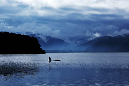 man in boat between ocean during twilight thumbnail