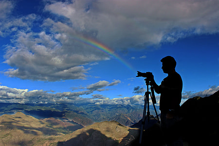 grayscale photography of man holding camera with tripod thumbnail