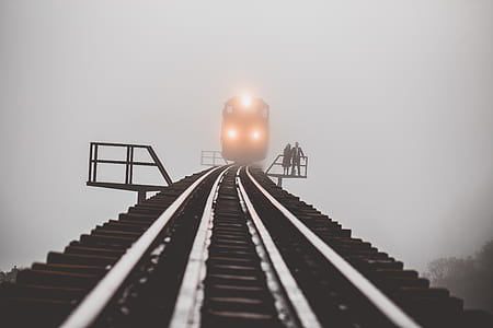 photograph of two people standing on waiting area beside transit track thumbnail