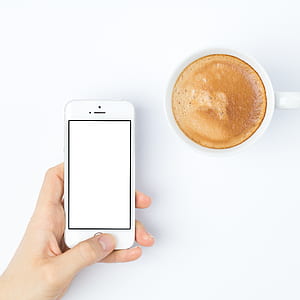 person holding silver iPhone 5s near white ceramic coffee cup with coffee thumbnail
