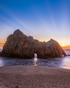brown rock formation on sea during sunrise thumbnail